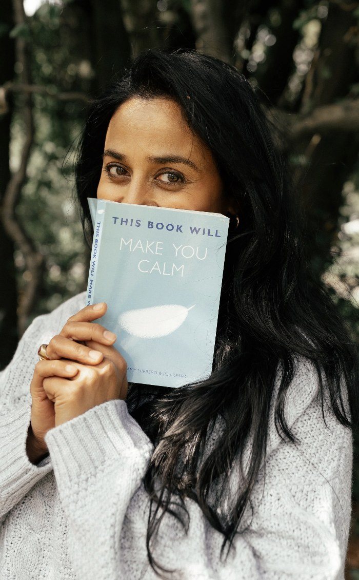 Woman holding a book up to her face in woodland