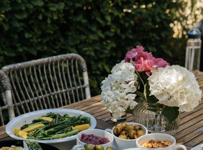 Outdoor table set with vegetables and white hydrangeas